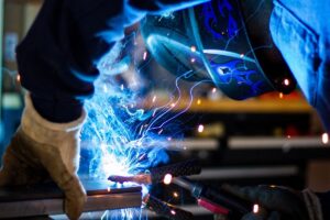 person welding with smoke and fumes that industrial ventilation systems must remove