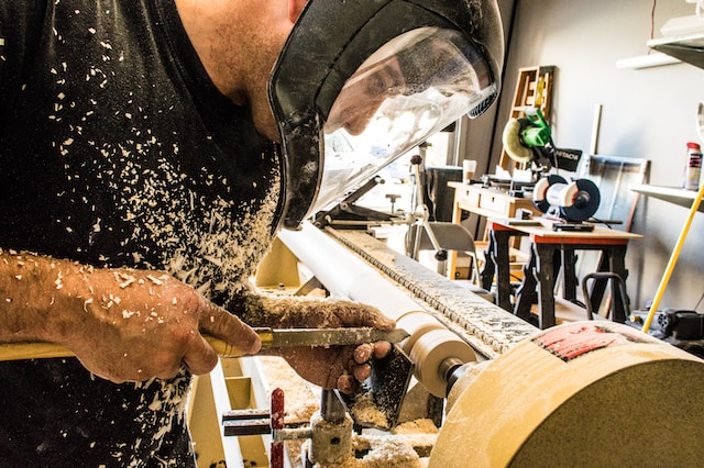 Worker in woodworking facility creating sawdust that the industrial exhaust system will remove.